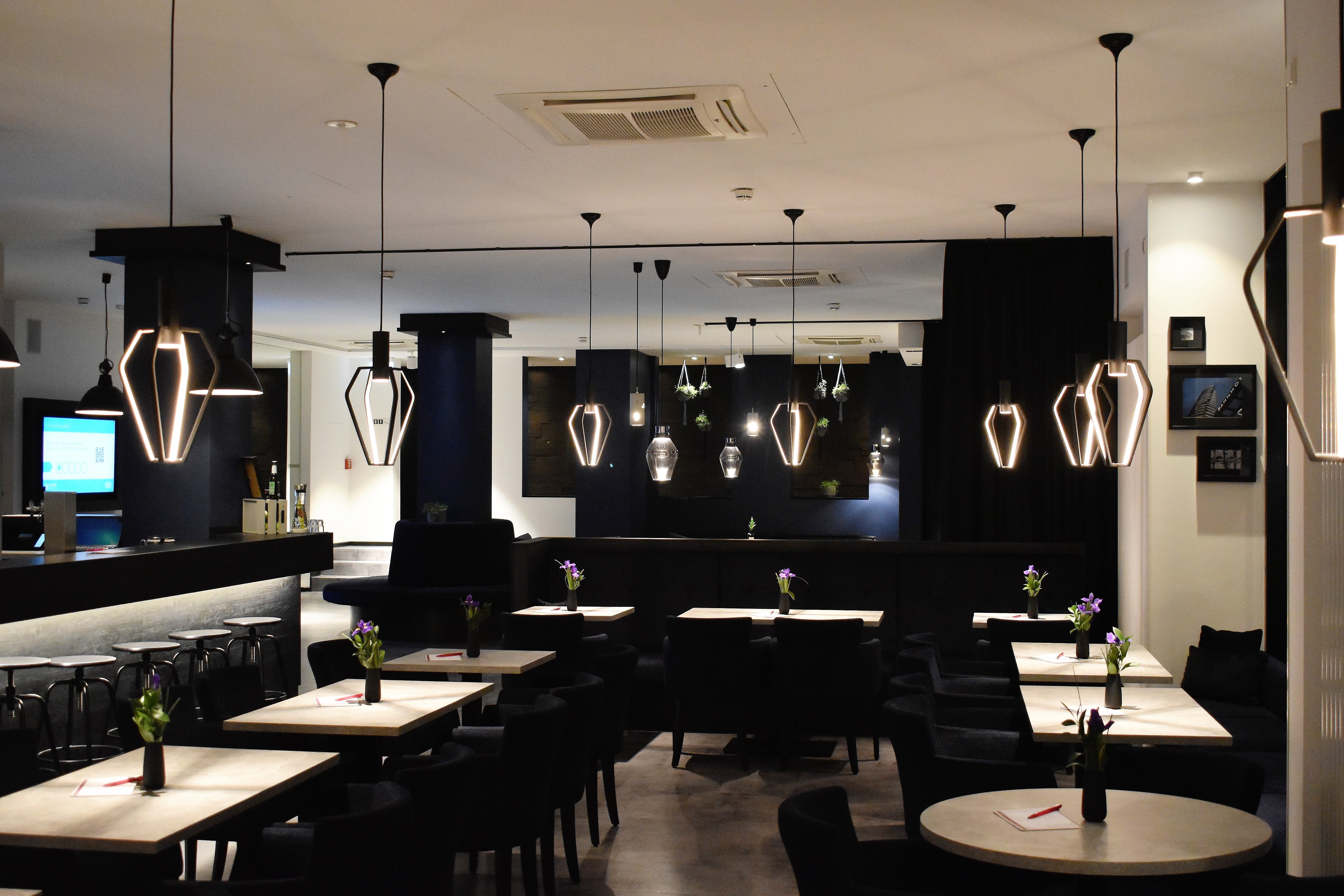 A picture of an interior of a restaurant with tables set and lights hanging